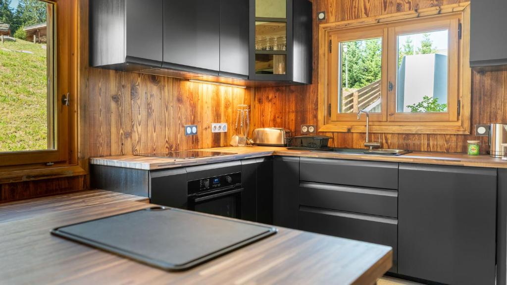 - une cuisine avec des appareils noirs et un mur en bois dans l'établissement Chalet Vallée de Chamonix Randonnées, Rafting et Spa, à Saint-Gervais-les-Bains 29 autres photos