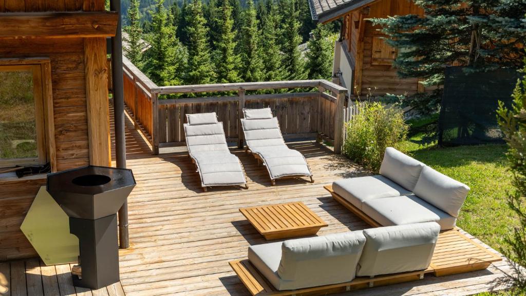 une terrasse en bois avec des chaises longues et un grill dans l'établissement Chalet Vallée de Chamonix Randonnées, Rafting et Spa, à Saint-Gervais-les-Bains