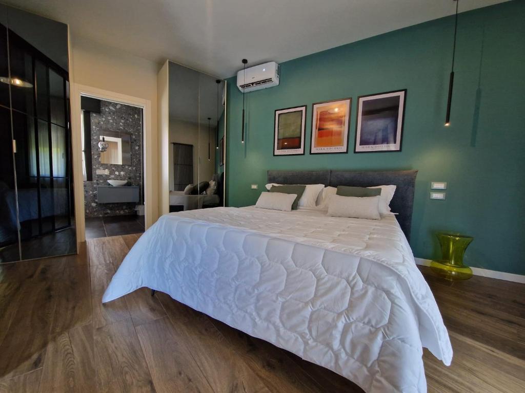 une chambre avec un grand lit blanc avec un mur vert dans l'établissement Hotel Ragno D'Oro, à Sottomarina