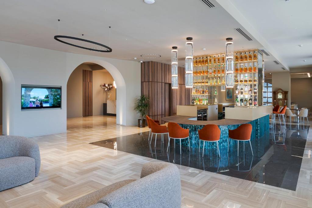 - un hall avec un bar pourvu de chaises orange dans l'établissement Sant Alphio Garden Hotel & SPA, à Giardini Naxos