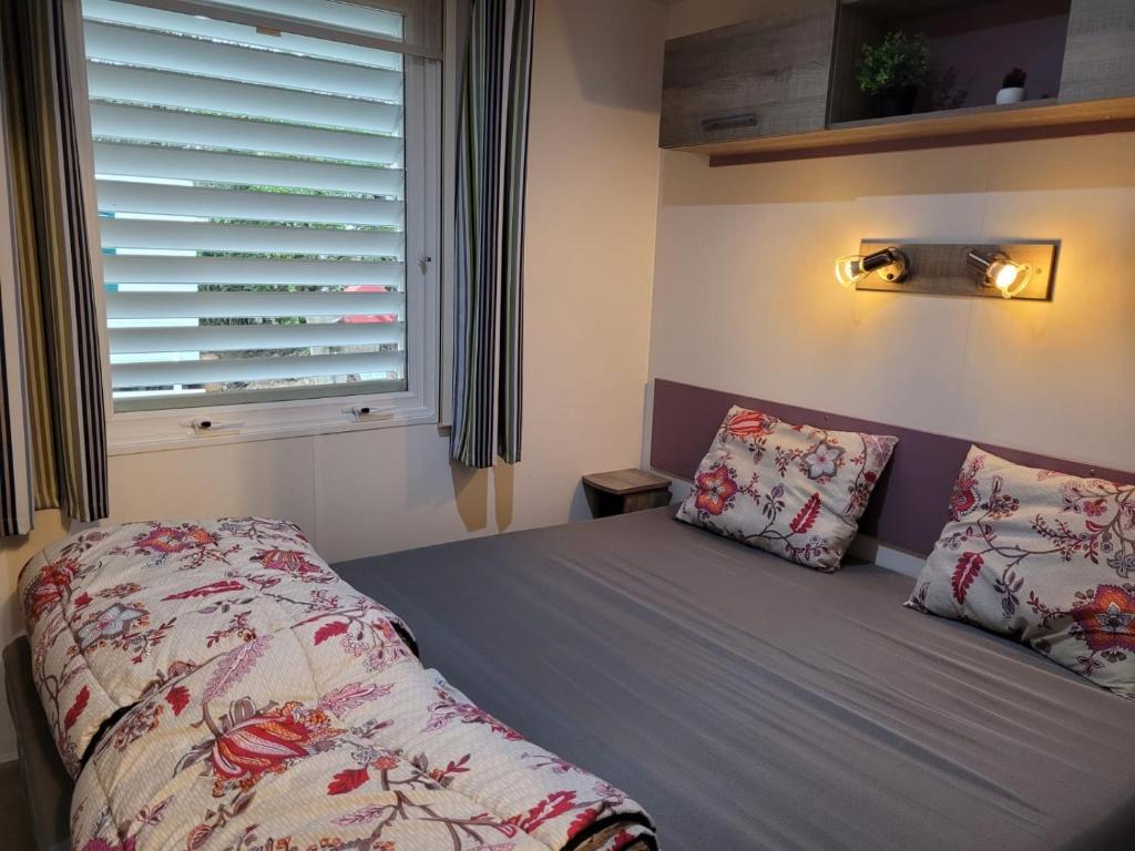 Ce lit se trouve dans un dortoir doté d'une fenêtre et d'un lit avec des oreillers. dans l'établissement Chalet Coco, à Roquebrune-sur Argens