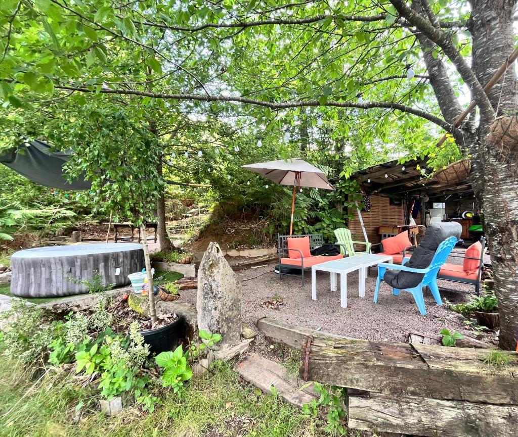 un patio avec une table, des chaises et un parasol dans l'établissement Bateaupirate19, à Cornil