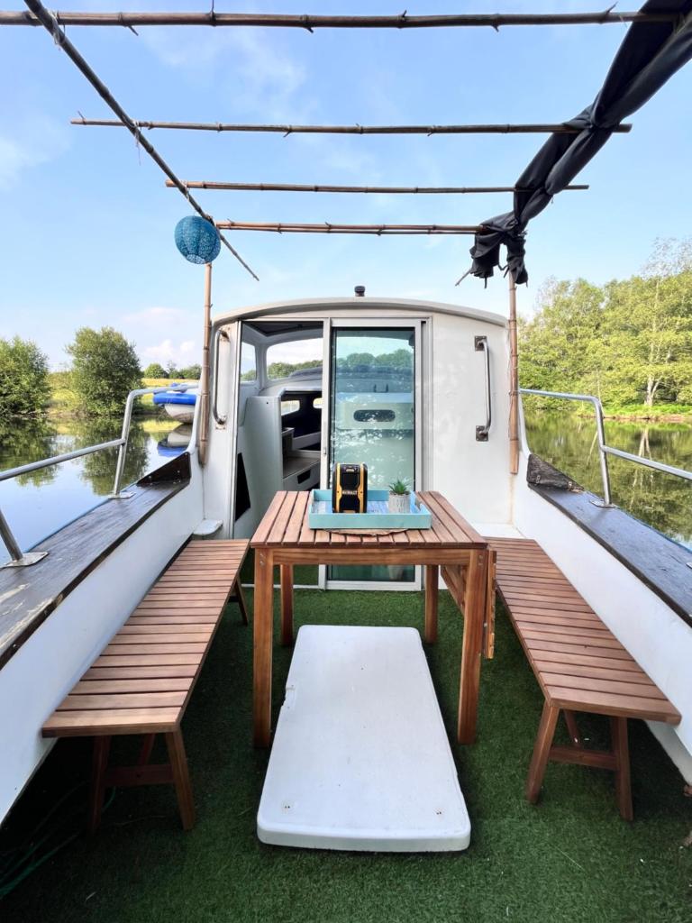 une table en bois sur un bateau avec bancs dans l'établissement Bateaupirate19, à Cornil