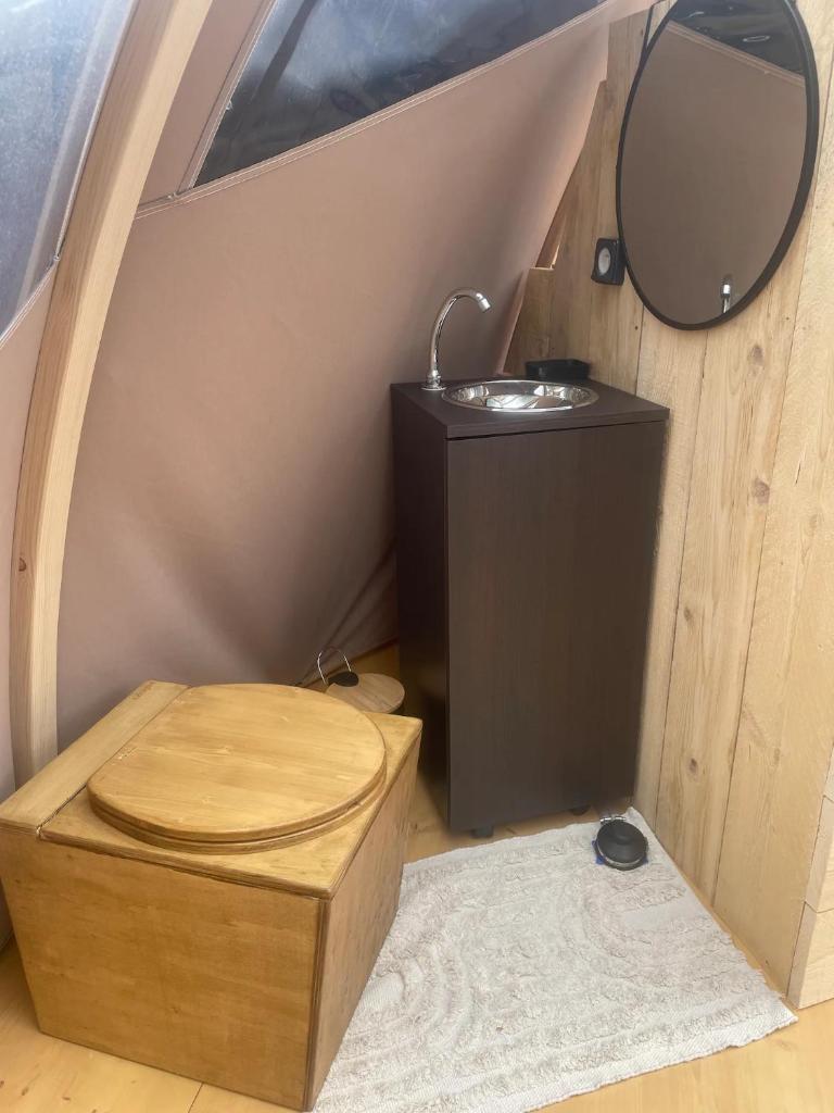La salle de bains est pourvue de toilettes en bois et d'un miroir. dans l'établissement Bulle insolite Wigwam, à Aulnay-sur-Iton
