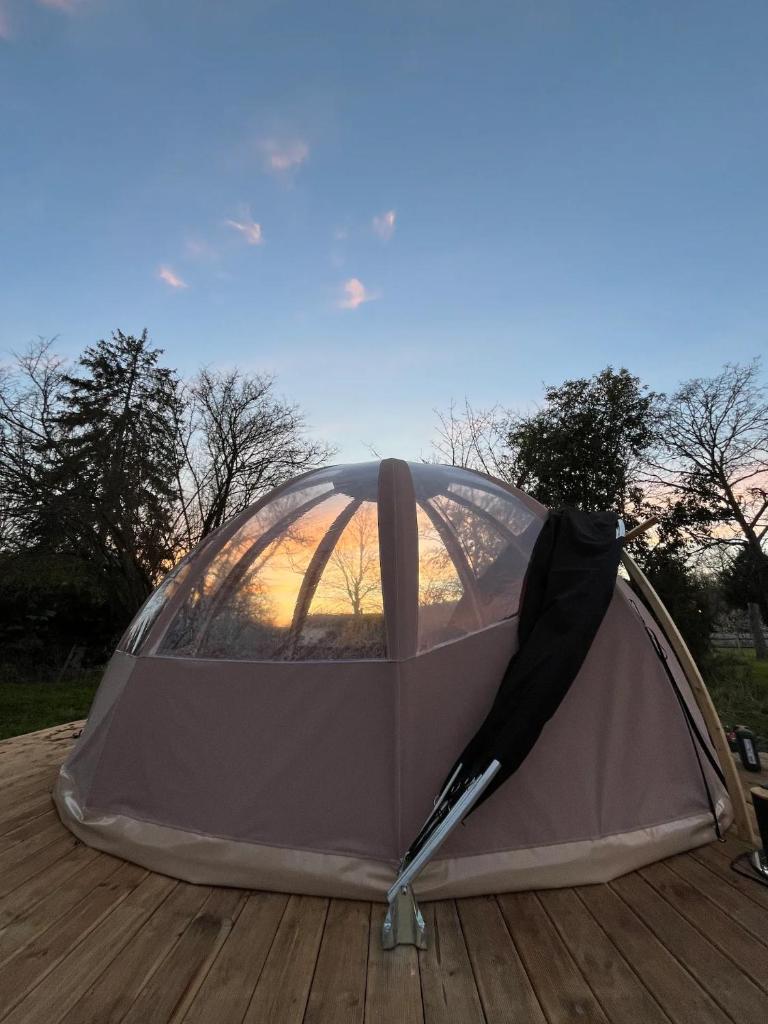 une tente avec un parasol assise sur une terrasse dans l'établissement Bulle insolite Wigwam, à Aulnay-sur-Iton 2 autres photos