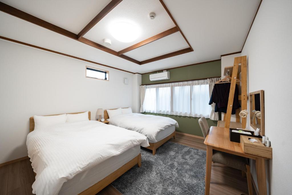 Cette chambre comprend deux lits et une table avec un miroir. dans l'établissement 素泊り旅館 Yururi, à Yufu