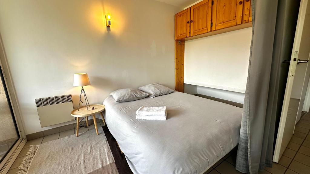 une petite chambre avec un lit et une table dans l'établissement Appartement Centre Ville pied de piste Briançon, à Briançon