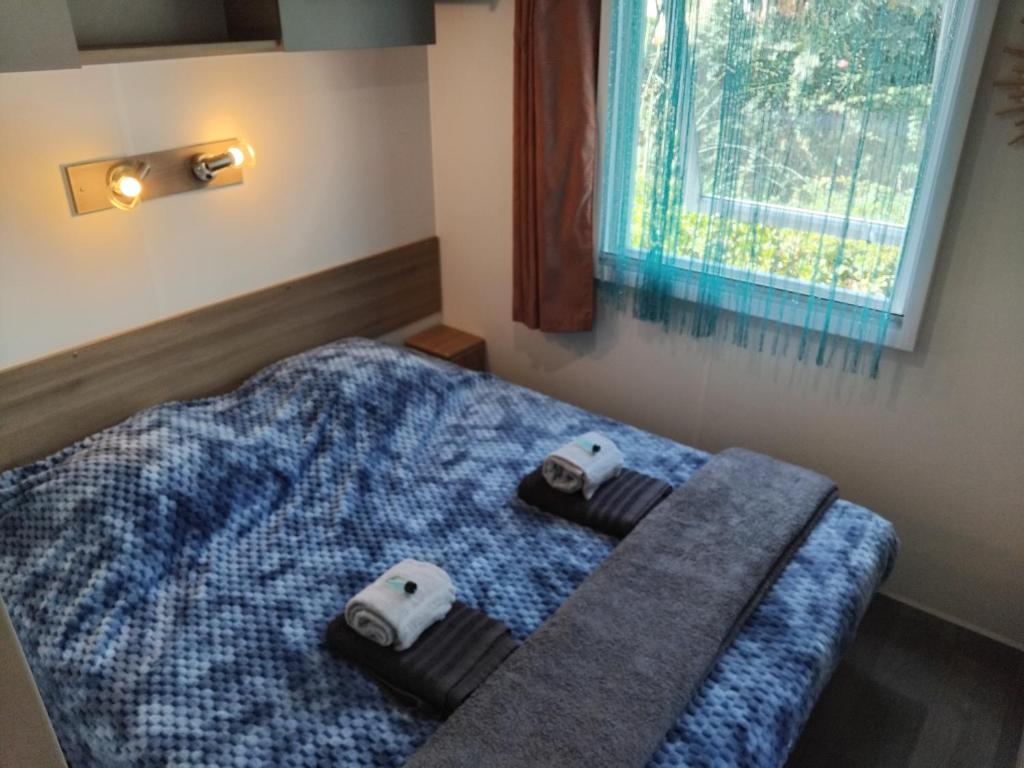 une chambre avec un lit avec deux serviettes dessus dans l'établissement MOBIL HOME GLAMPING CONFORT D'UN HOTEL SANS LES CONTRAINTES PISCINE PROMOTION SEPTEMBRE 3 CHAMBRES - 2 SdB -climatisé - 300m de la mer - piscine - parking -, à Hyères