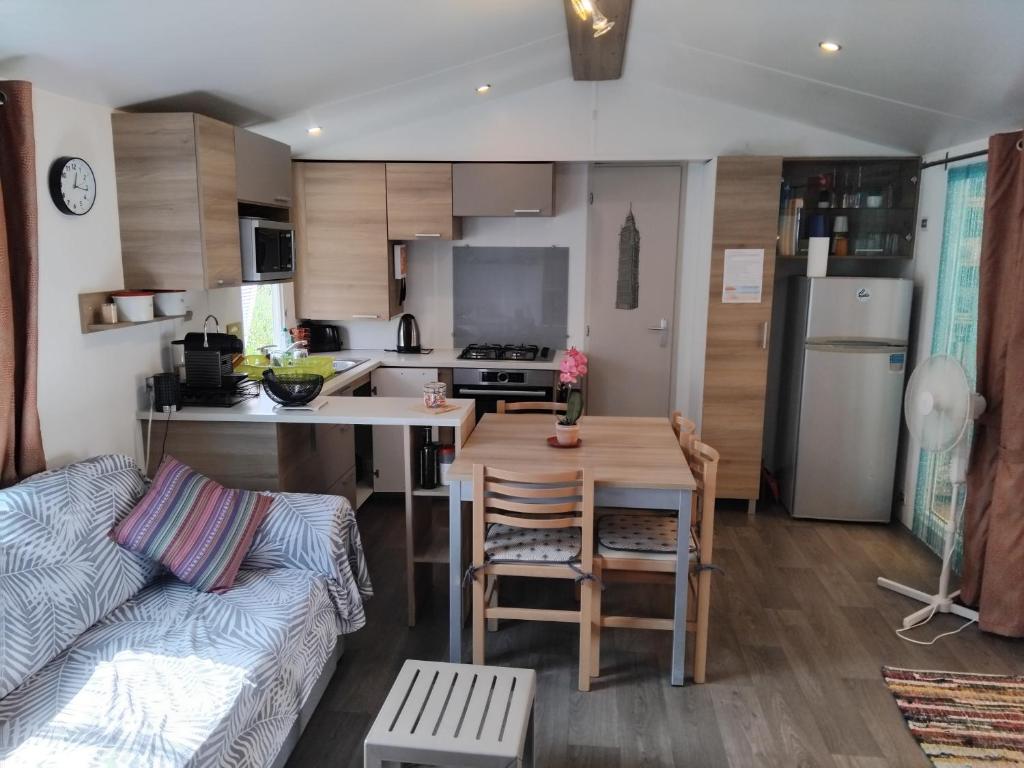 une cuisine et un salon avec une table et un canapé dans l'établissement MOBIL HOME GLAMPING CONFORT D'UN HOTEL SANS LES CONTRAINTES PISCINE PROMOTION SEPTEMBRE 3 CHAMBRES - 2 SdB -climatisé - 300m de la mer - piscine - parking -, à Hyères
