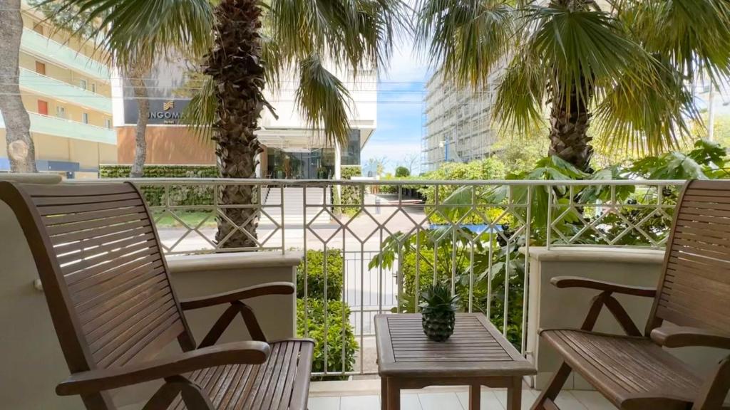 2 chaises et une table sur un balcon avec des palmiers dans l'établissement Residence Lungomare - Charming apartments, à Riccione
