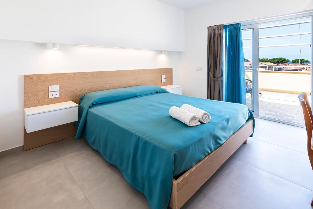 une chambre avec un lit avec des draps bleus et une fenêtre dans l'établissement Hotel Maria, à Castellabate