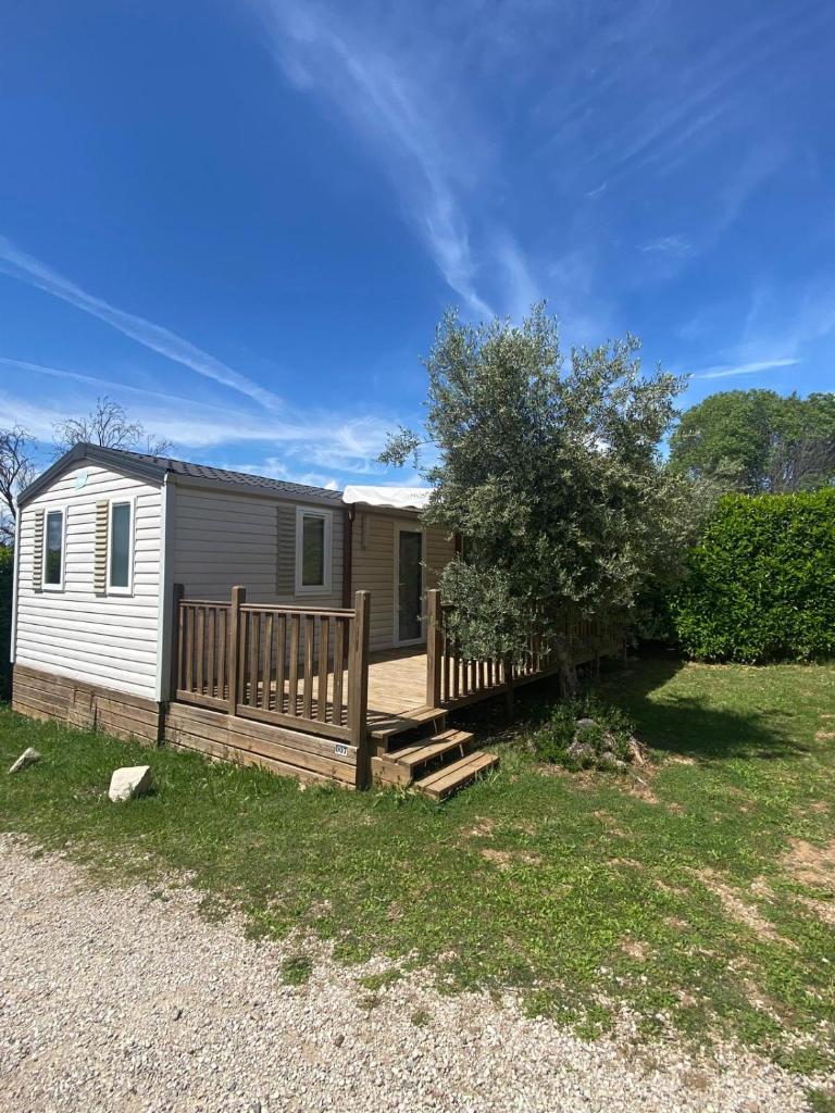 un mobile home avec une terrasse et une clôture dans l'établissement Camping les Oliviers, à Oraison