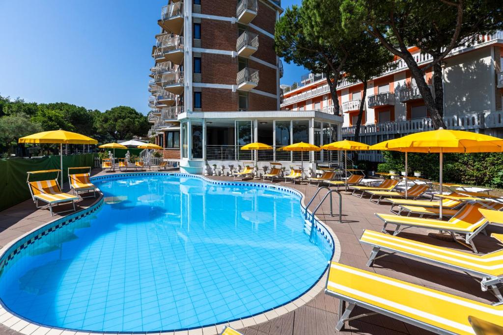 une grande piscine avec chaises et parasols dans l'établissement Hotel La Siesta, à Lido di Jesolo