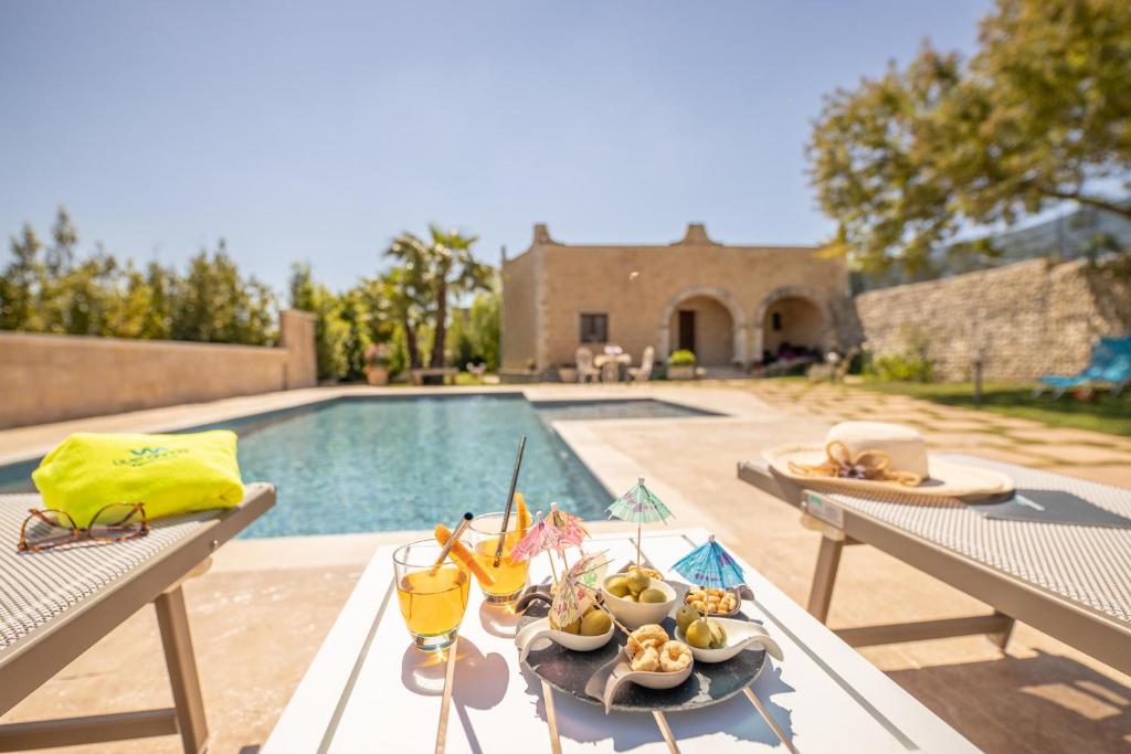 une table avec de la nourriture dessus à côté d'une piscine dans l'établissement Villa Funny, à Carpignano Salentino