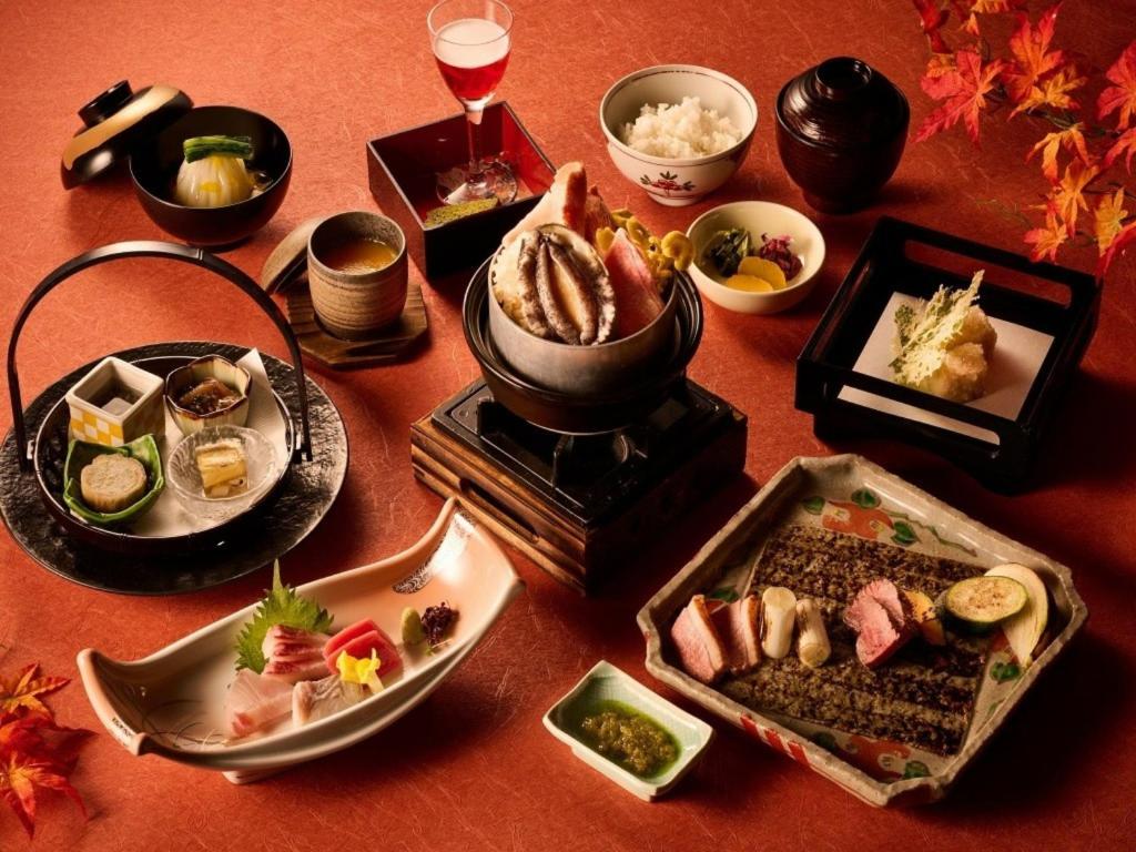 une table avec des assiettes de nourriture et un pot de nourriture dans l'établissement Laforet Ito Onsen Yunoniwa, à Itō