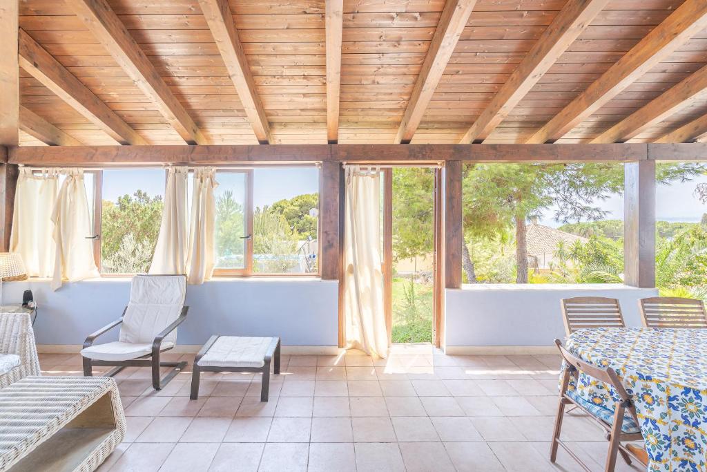 une pièce avec une table, des chaises et des fenêtres dans l'établissement La Casa del Vento Plemmirio, à Plemmirio