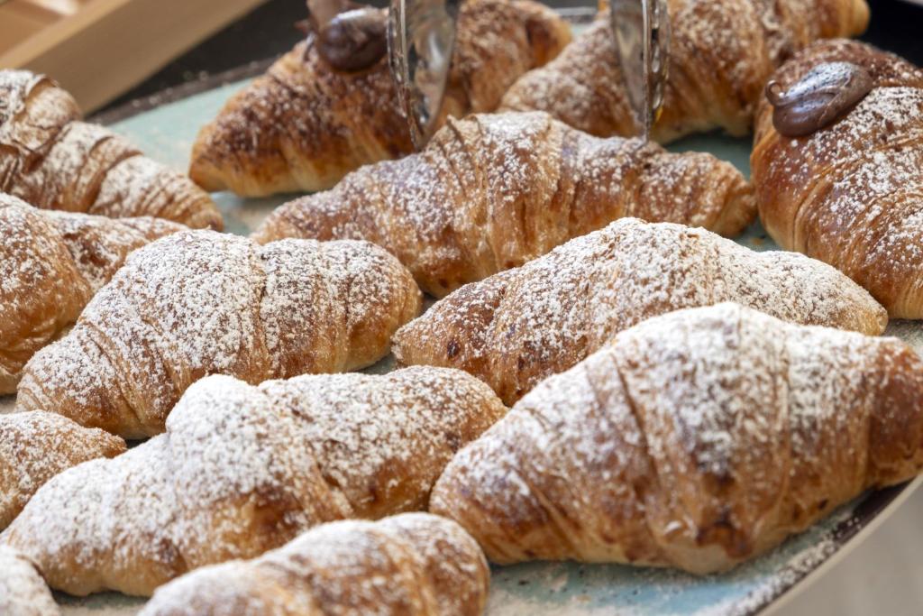 un tas de beignets avec du sucre en poudre sur un plateau dans l'établissement MClub Del Golfo, à Sorso