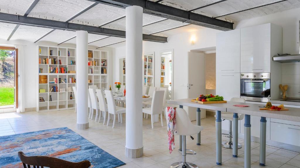 une cuisine avec des colonnes blanches et une table et des chaises dans l'établissement VILLA ARDENTE 12&1, Emma Villas, à Bellante