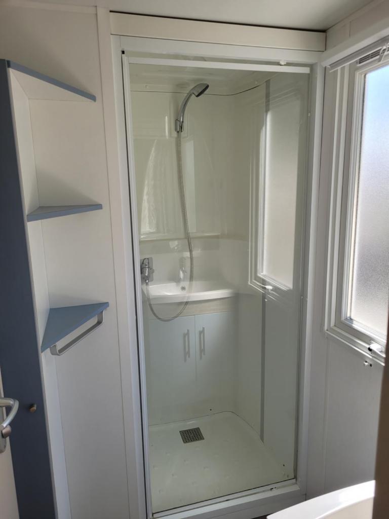 une salle de bain avec une douche en verre et un lavabo dans l'établissement mobil home, à Claouey