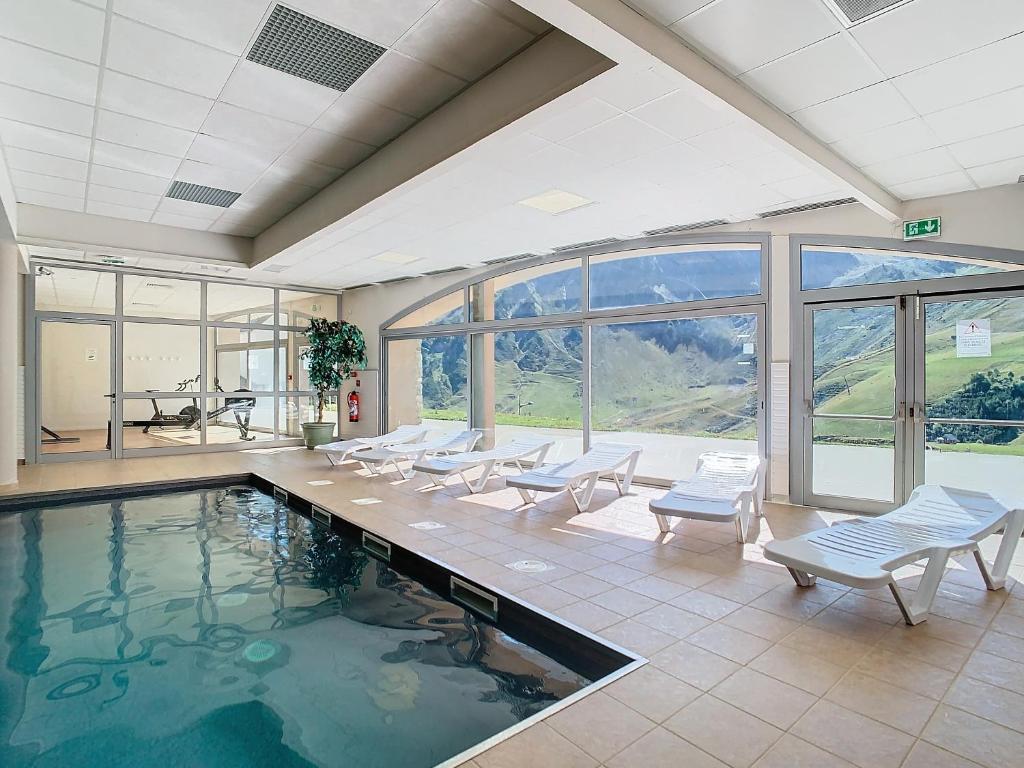 une piscine intérieure avec des chaises blanches et une grande fenêtre dans l'établissement Appartement 2 chambres en duplex à La Mongie, à La Mongie