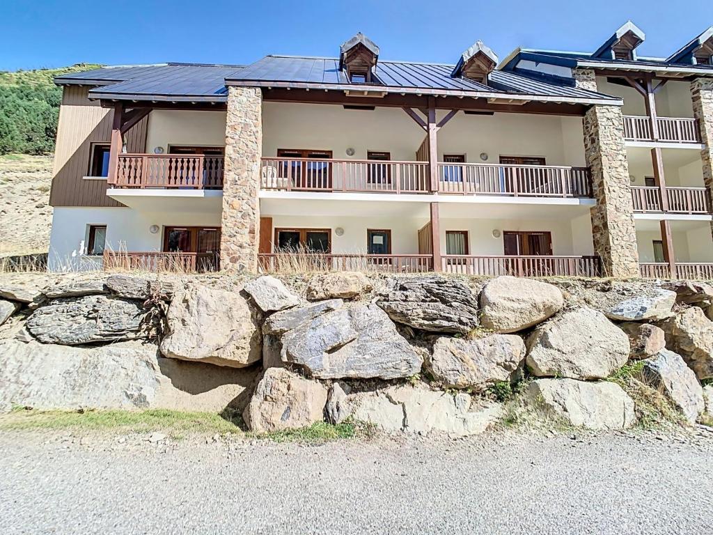 une grande maison avec un mur de roche devant elle dans l'établissement Appartement 2 chambres en duplex à La Mongie, à La Mongie