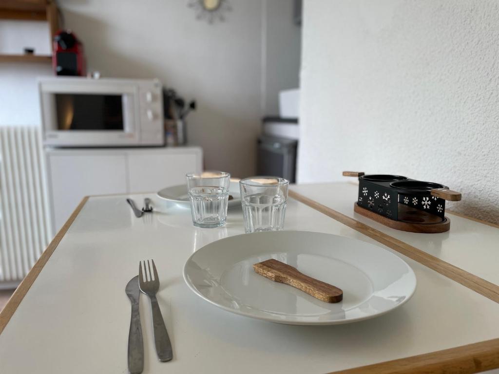 une table avec une plaque blanche et un couteau et une fourchette dans l'établissement Studio accès direct à la Croisette, au coeur des Menuires, aux Menuires