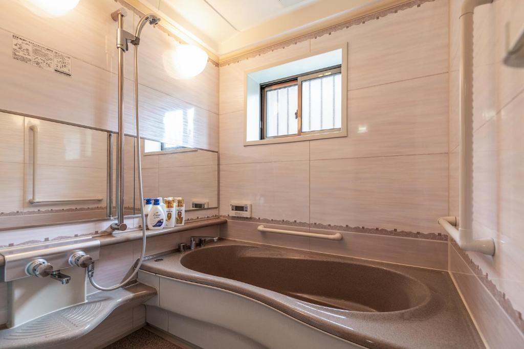 une salle de bain avec une grande baignoire et une fenêtre dans l'établissement Rakushinkan Villa, à Yufu