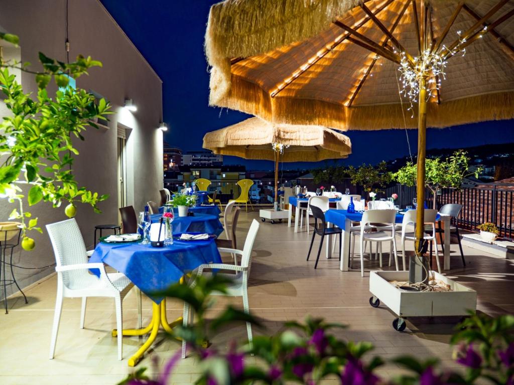 un restaurant avec des tables bleues, des chaises et des parasols dans l'établissement Hotel Antagos, à Montesilvano