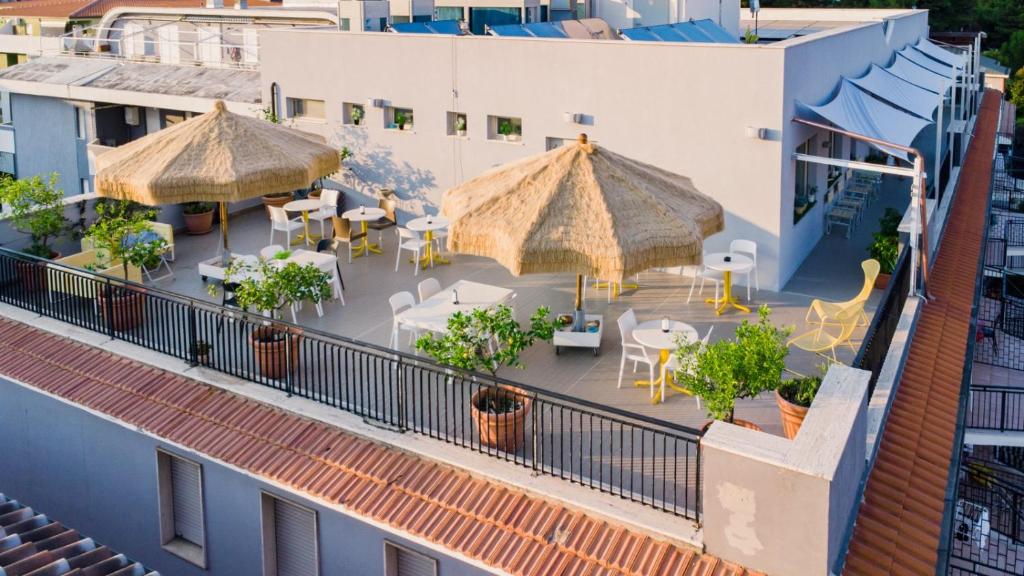 un patio extérieur avec des tables et des parasols dans un bâtiment dans l'établissement Hotel Antagos, à Montesilvano