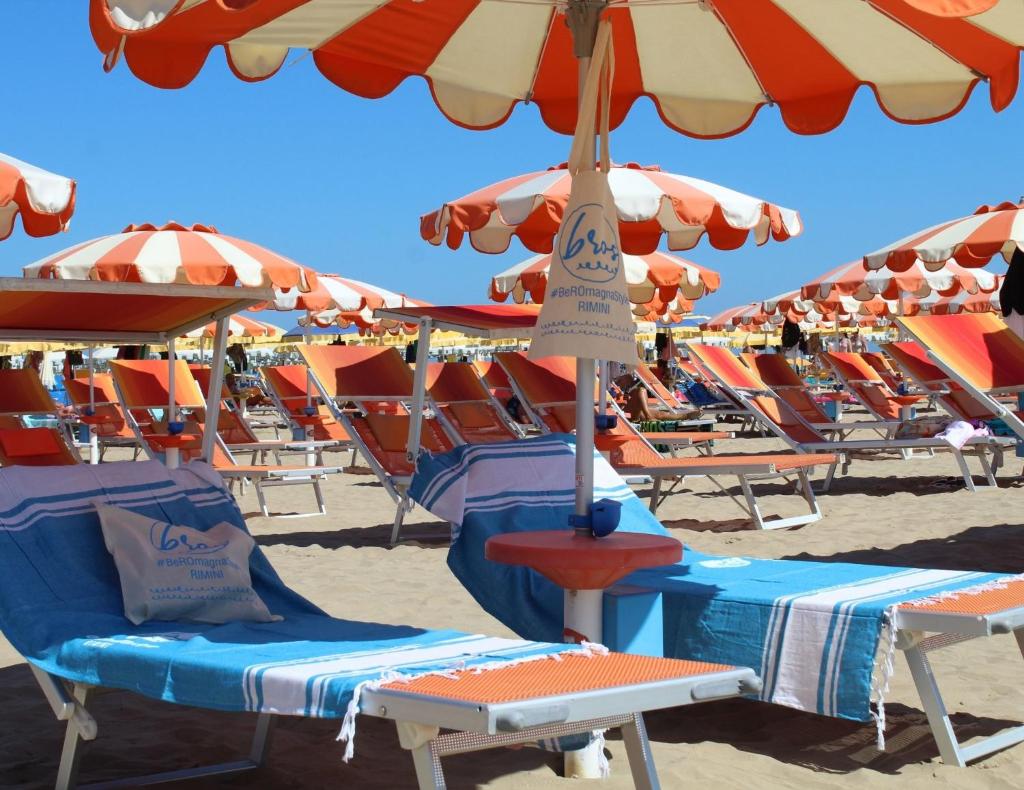 un groupe de chaises et de parasols sur une plage dans l'établissement Hotel Villa del Parco, à Rimini