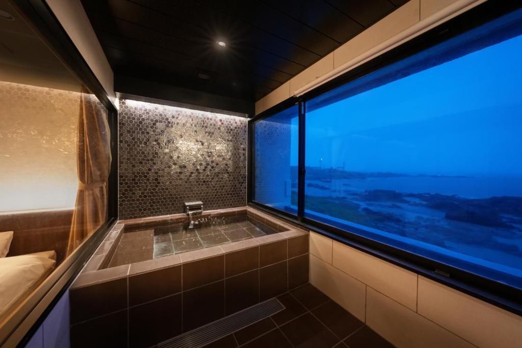 une salle de bain avec baignoire et une grande fenêtre dans l'établissement 季粋の宿 紋屋, à Hongō