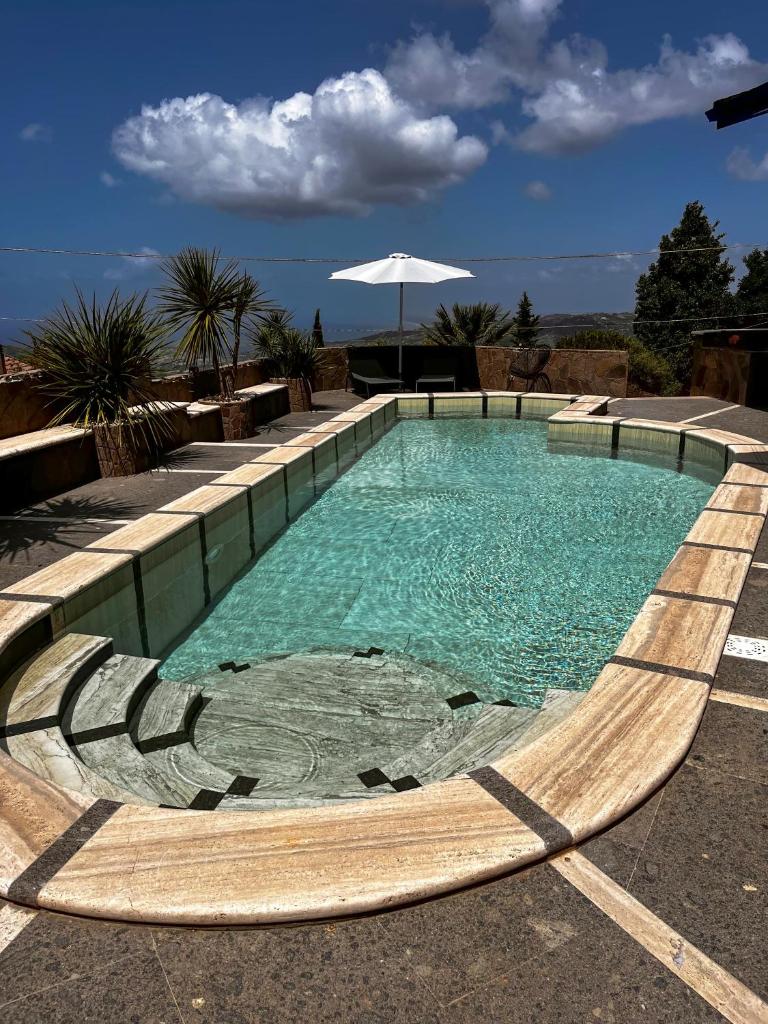 - une piscine d'eau bleue avec un parasol dans l'établissement Villa Lila, à Laureana Cilento