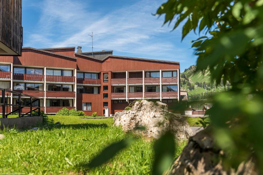 un bâtiment en face d'un champ vert dans l'établissement Résidence Pierre & Vacances Les Mouflons I et II, à Praz de Lys - Sommand