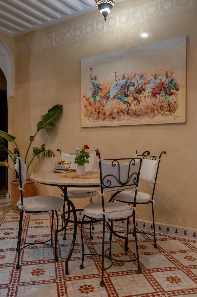une table et des chaises dans une pièce ornée d'un tableau mural dans l'établissement Riad Dar Tuscia, à Marrakech