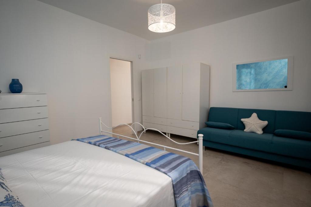 une chambre avec un lit et un canapé bleu dans l'établissement Leporano villa MADIA con piscina, Taranto, à Leporano Marina