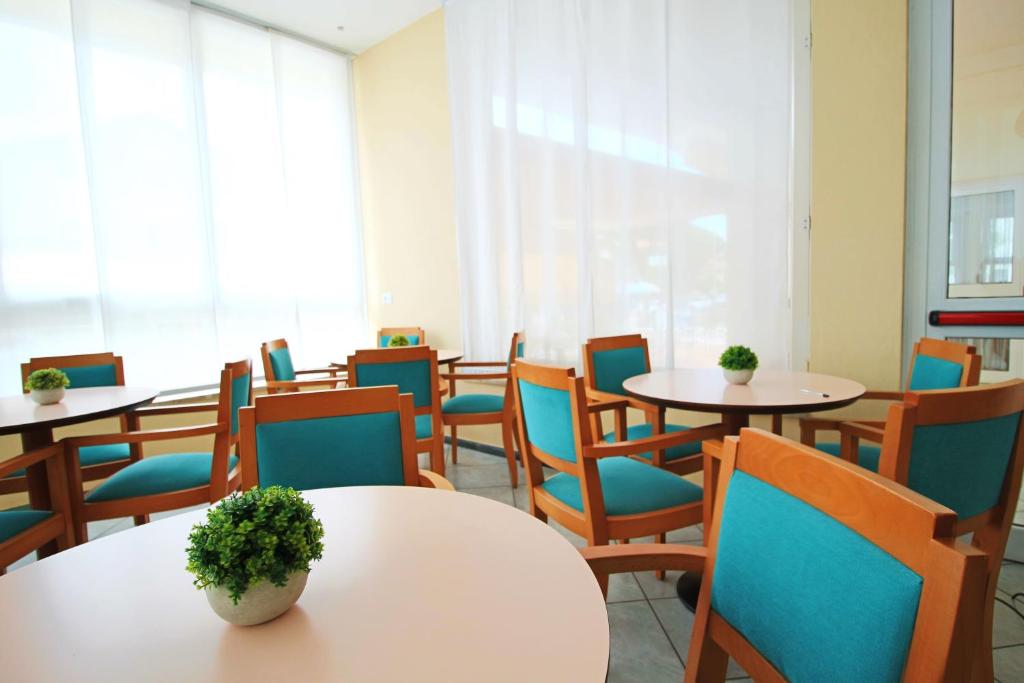 une salle d'attente avec des tables et des chaises avec des plantes dessus dans l'établissement Hotel Manuela, à Cervia