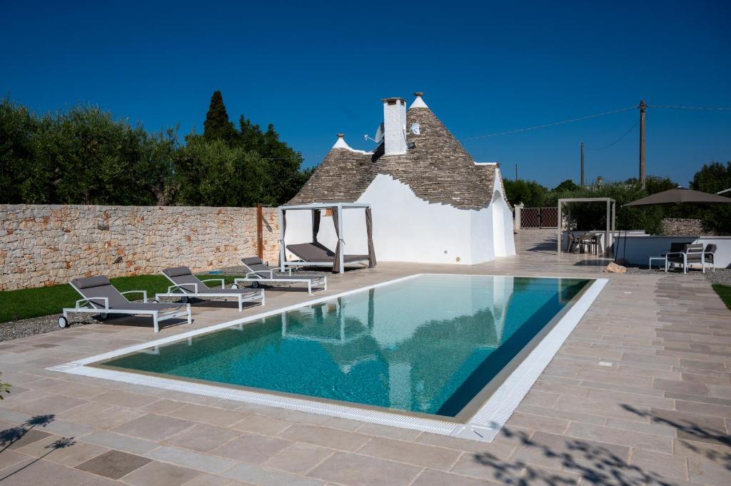 une piscine dans une cour avec des chaises et une maison dans l'établissement PALACHARME - Trulli Luxury, à Alberobello