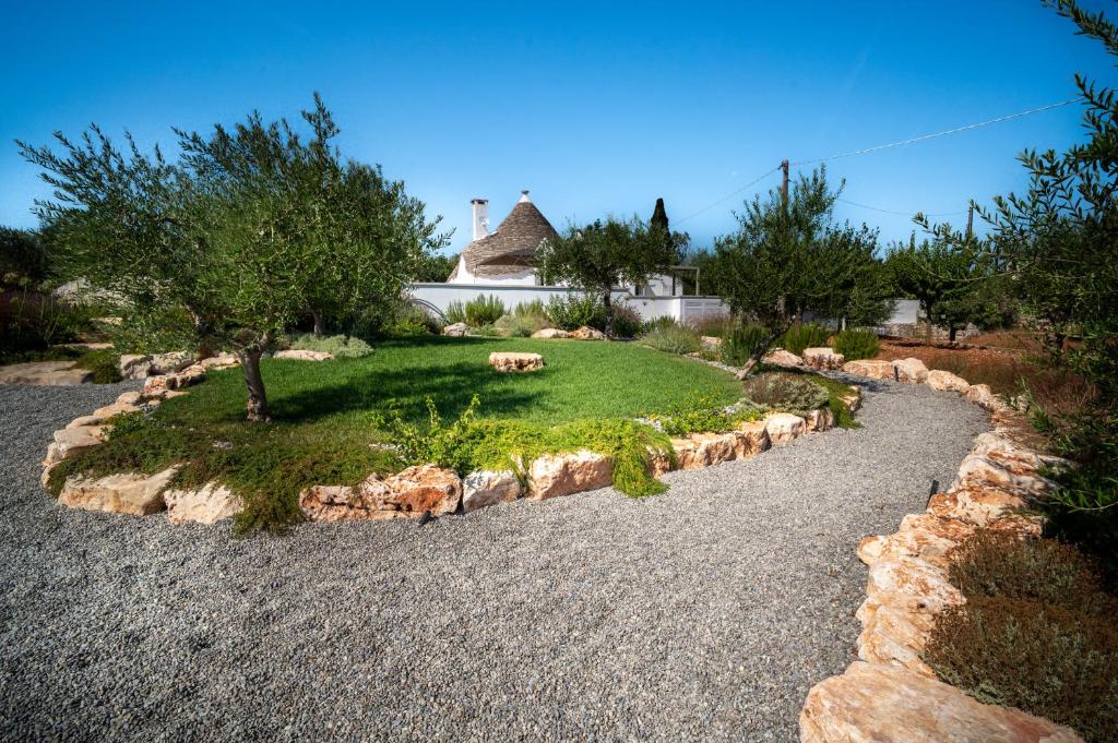 un jardin avec des rochers, un arbre et une maison dans l'établissement PALACHARME - Trulli Luxury, à Alberobello