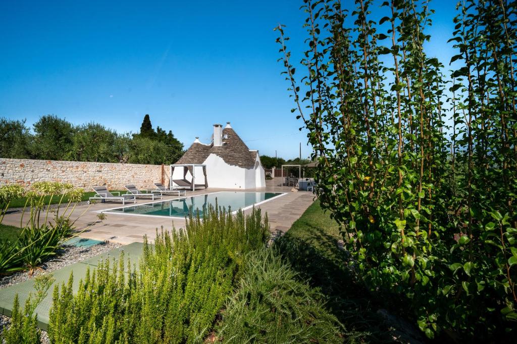 une maison avec une piscine dans un jardin dans l'établissement PALACHARME - Trulli Luxury, à Alberobello