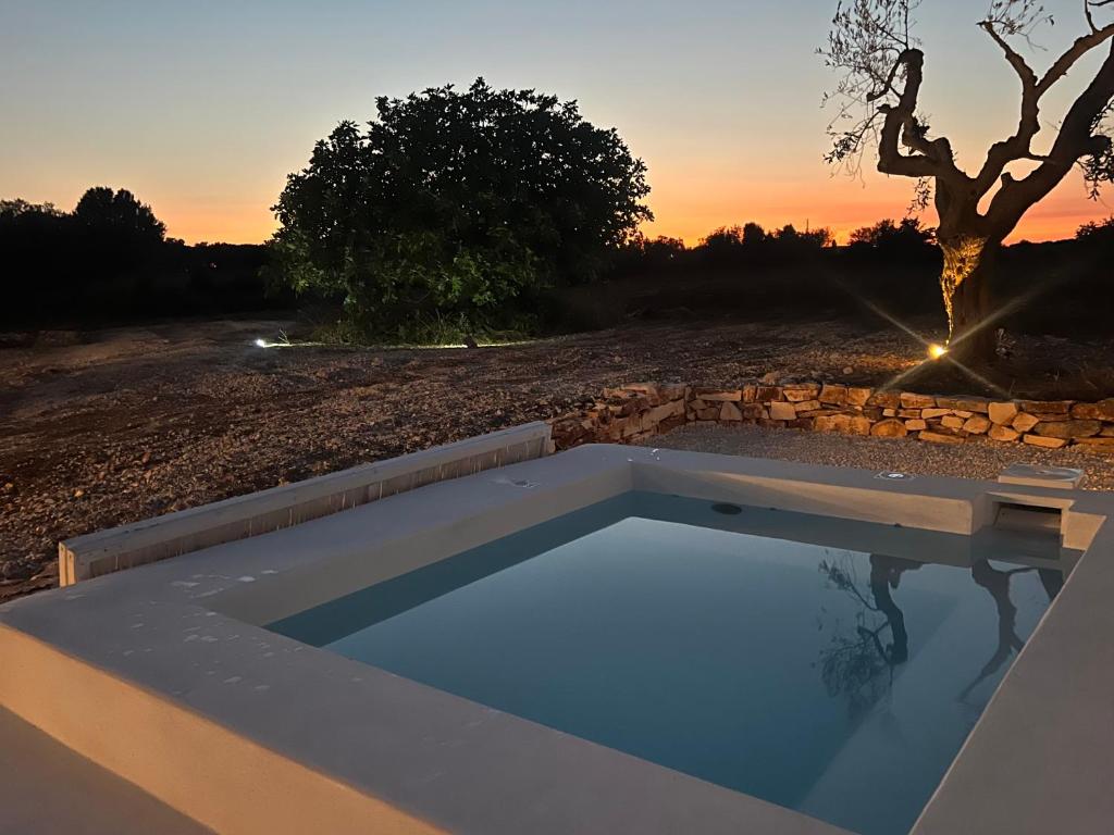 une piscine avec un coucher de soleil en arrière-plan dans l'établissement Trulli Pace 1879 Martina Franca, à Martina Franca