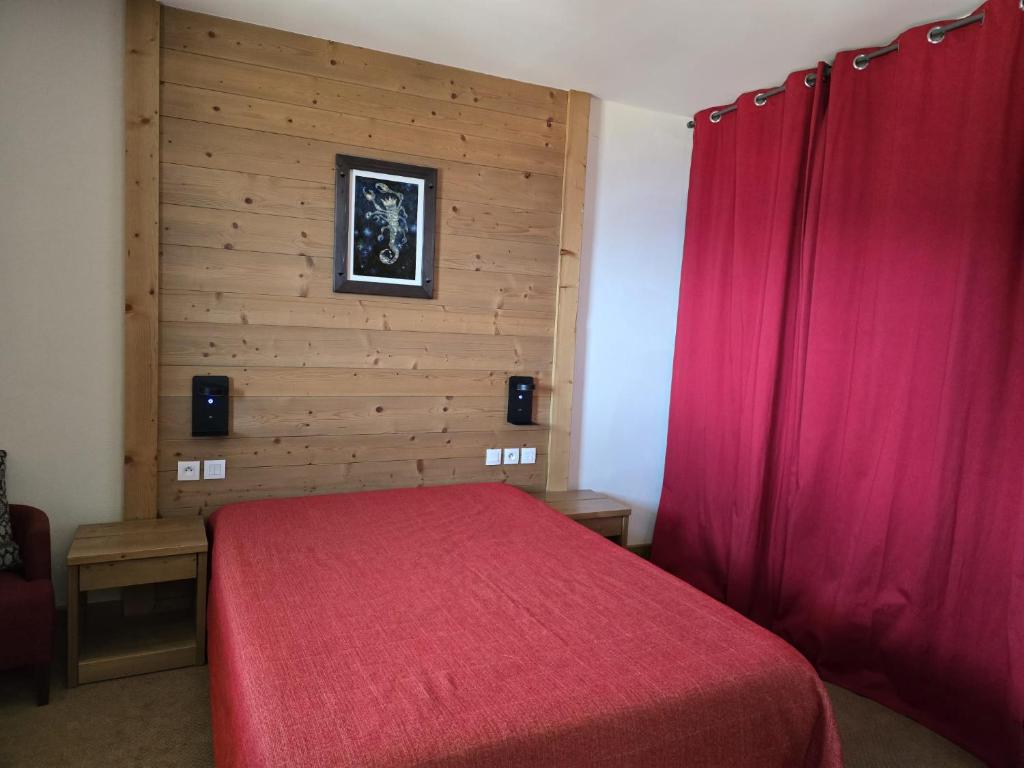 - une chambre avec un lit rouge et un mur en bois dans l'établissement Super appart Risoul Alpes du Sud, à Risoul