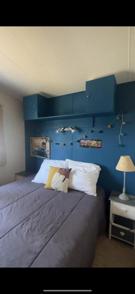 une chambre avec un grand lit avec un mur bleu dans l'établissement loue mobilhome 3 chambres, au Muy