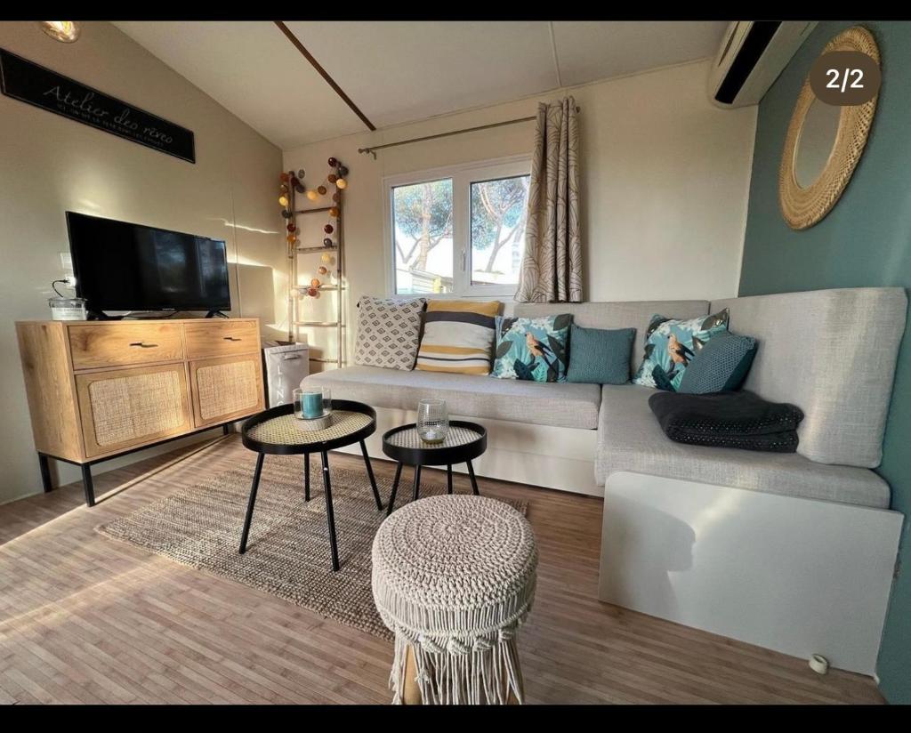 - un salon avec un canapé, 2 tables et une télévision dans l'établissement loue mobilhome 3 chambres, au Muy