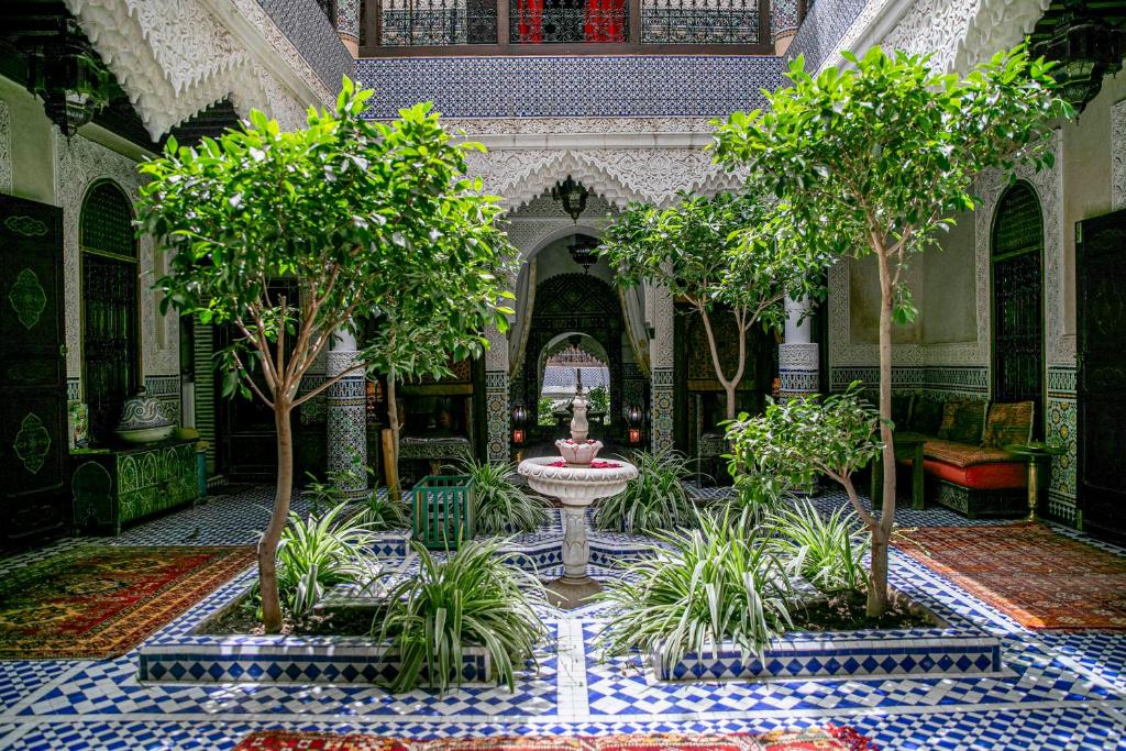 une cour avec une fontaine et des arbres dans un bâtiment dans l'établissement Riad Bab Chems, à Marrakech