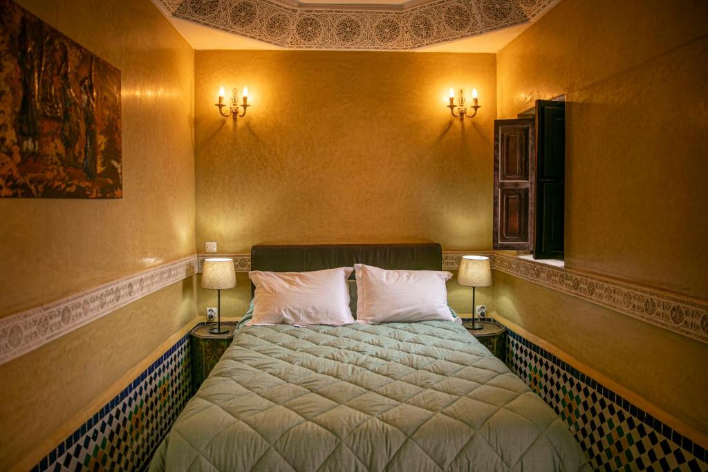 - une chambre avec un lit et deux lumières sur le mur dans l'établissement Riad Bab Chems, à Marrakech