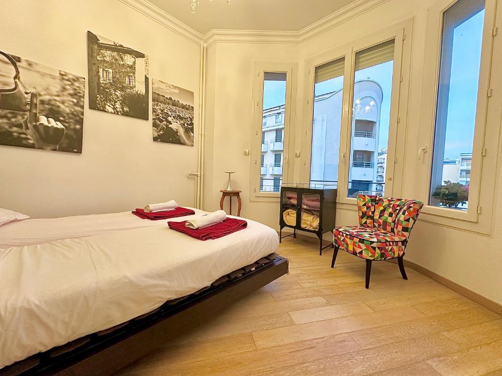 une chambre avec un lit, une chaise et des fenêtres dans l'établissement 3 pièces 100m2 balcon centre juan 2 pas des plages, à Antibes