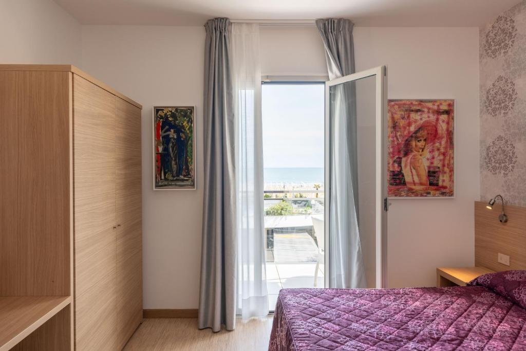 une chambre avec un lit et une grande fenêtre dans l'établissement Hotel Marzia Holiday Queen, à Caorle