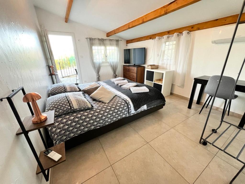 une chambre avec un lit, une table et un bureau dans l'établissement Gîte au milieu des vignes, à La Bruguière