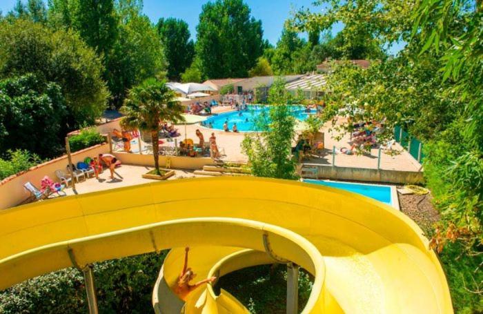 un toboggan jaune dans un complexe avec piscine dans l'établissement Mobilhome 5 place proche mer, à Angles