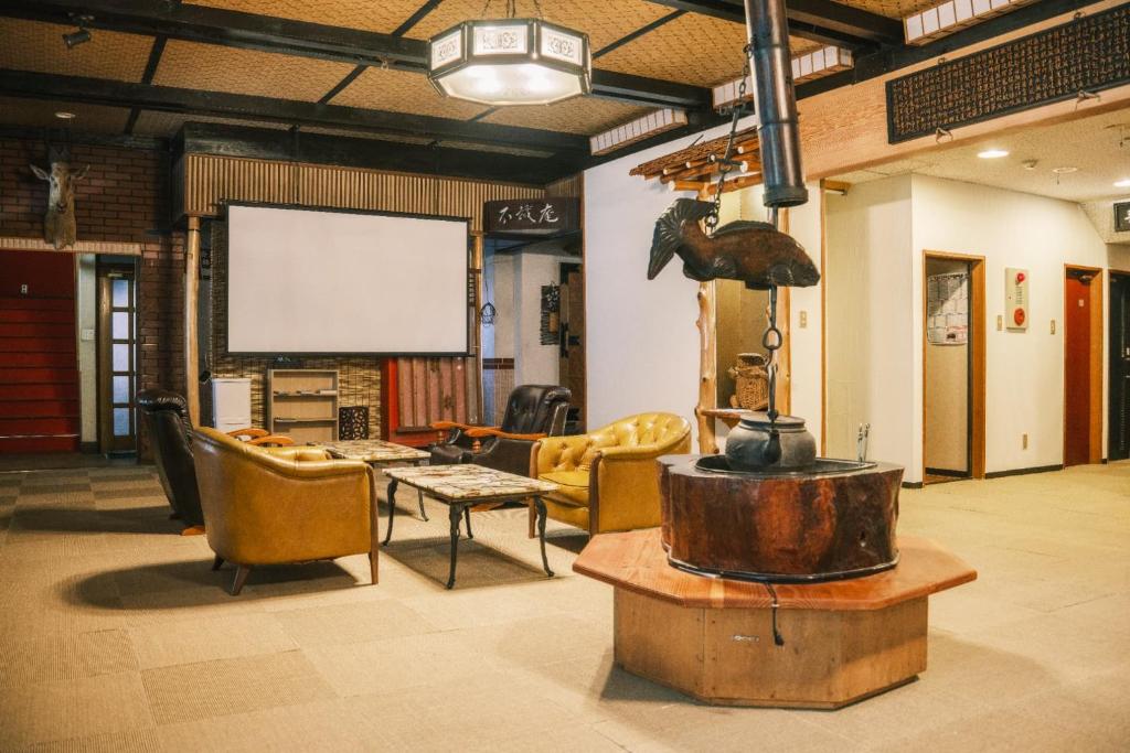 une chambre avec des chaises, une table et un écran dans l'établissement Myoko Tsubame onsen Iwatoya, à Myōkō